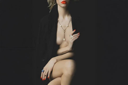 Vrouwelijk silhouet in halfduister, rode lippen en sieraden vangen het licht, een intieme en mysterieuze sfeer overheerst.