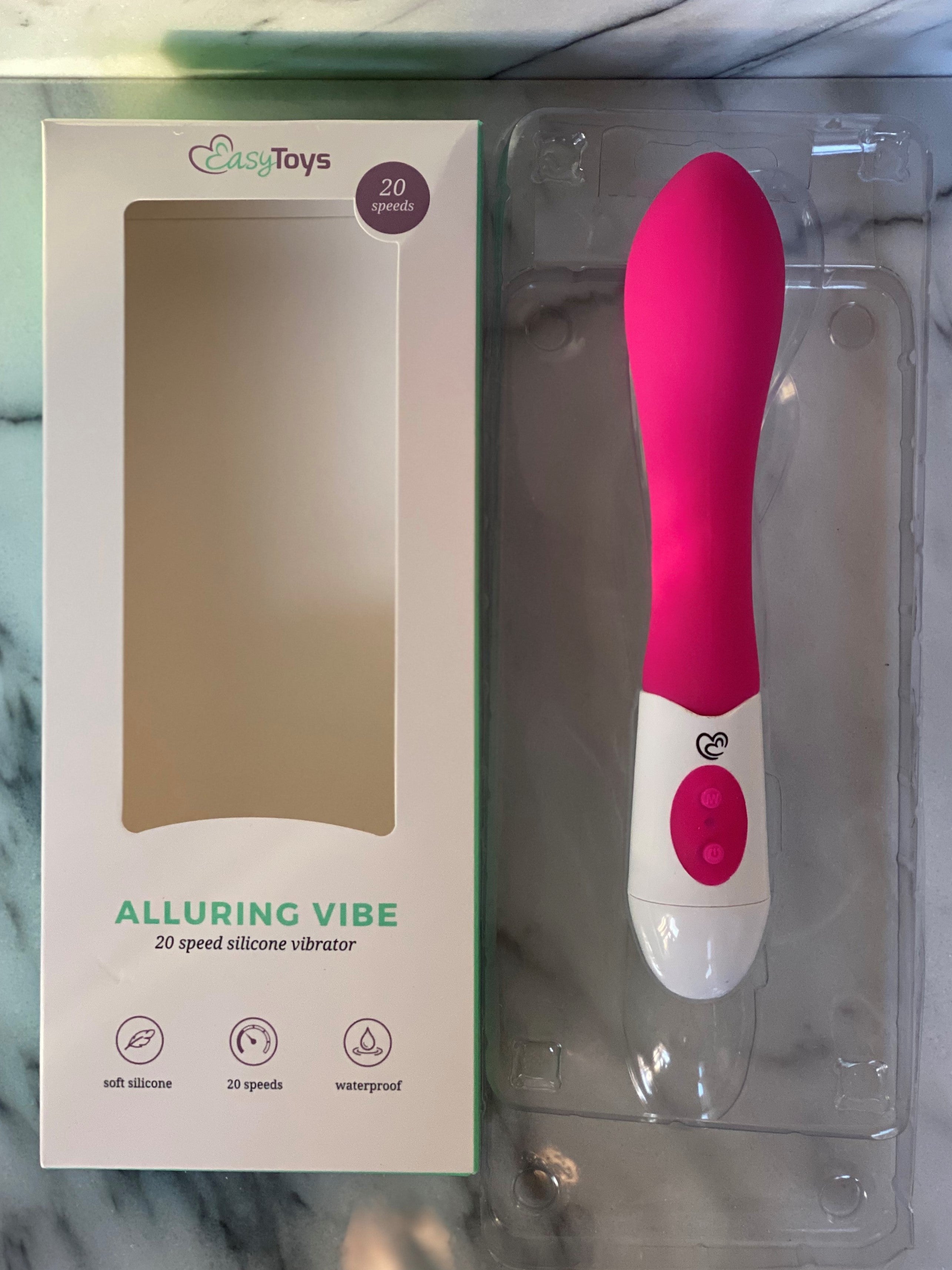 Geopende verpakking met roze-witte Alluring Vibe vibrator naast de doos