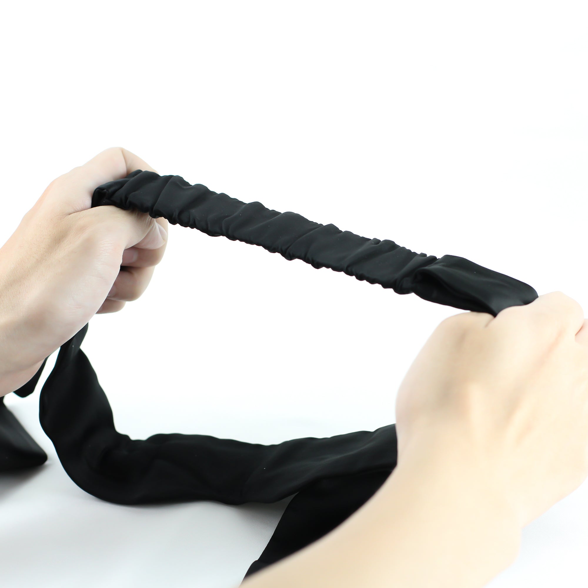 Handen rekken elastische band van zwarte blinddoek uit, flexibel draaggemak