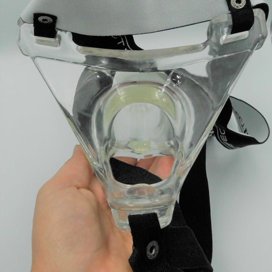 Achterzijde transparante holle prothese bevestigd aan zwart harnas, vastgehouden door hand