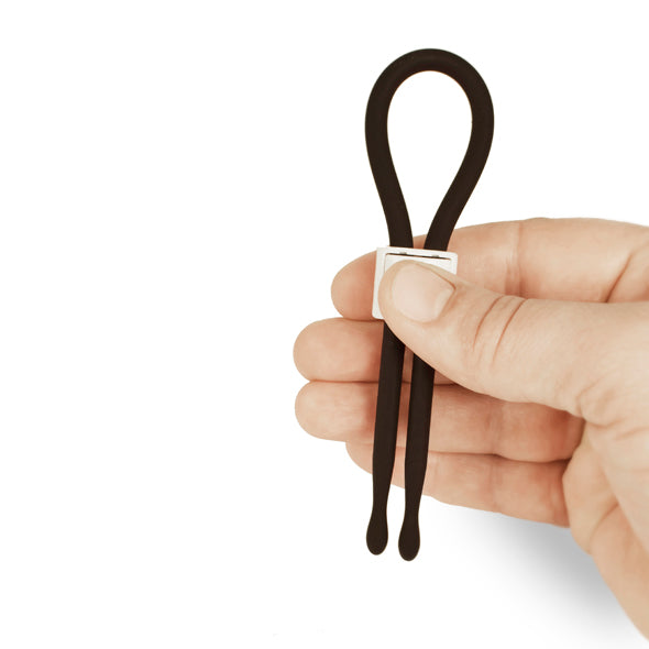 Verstelbare zwarte siliconen lasso cockring met schuifgesp, vastgehouden in hand