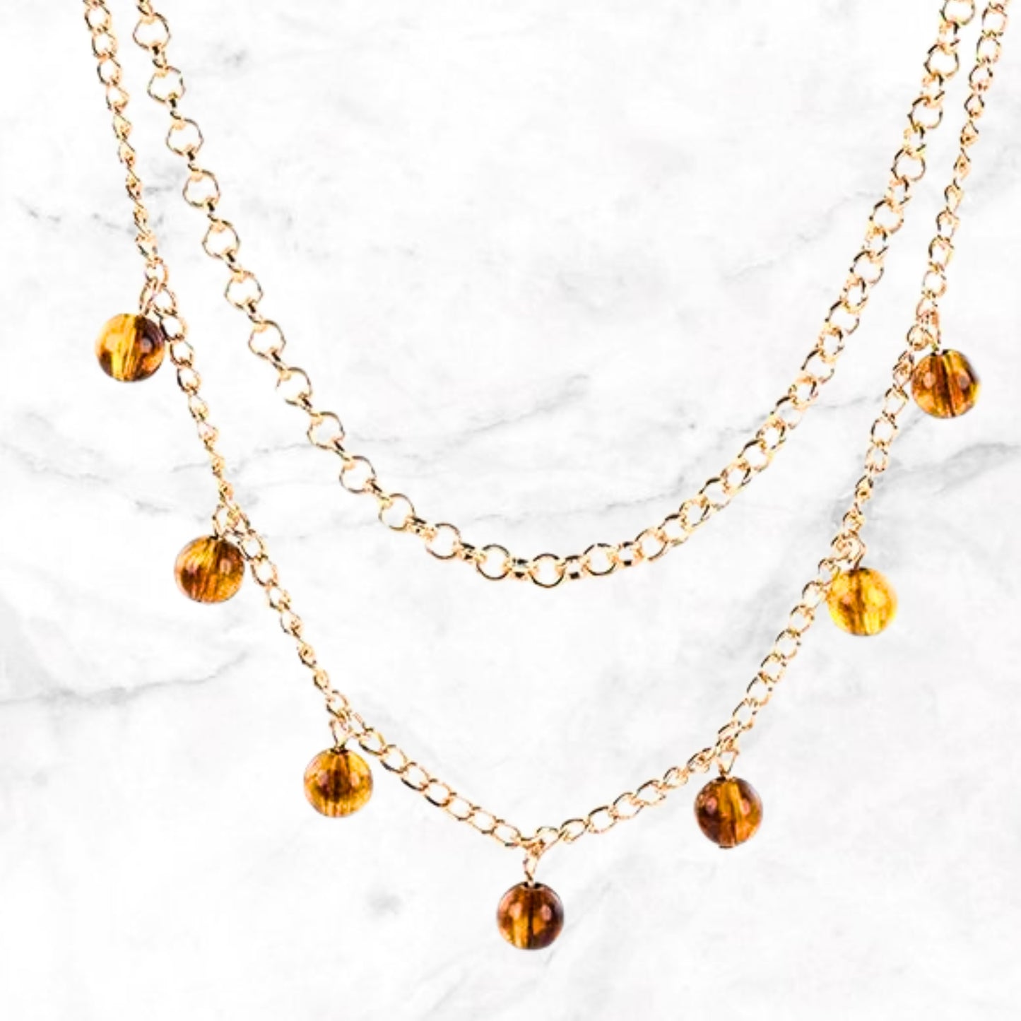 Tepelklemmetjes met goudkleurige ketting en amber steentjes