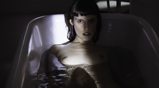 Vrouw met donker kort haar kijkt verleidelijk vanuit een bad in sfeervolle donkere belichting, XConfessions Vol. 6